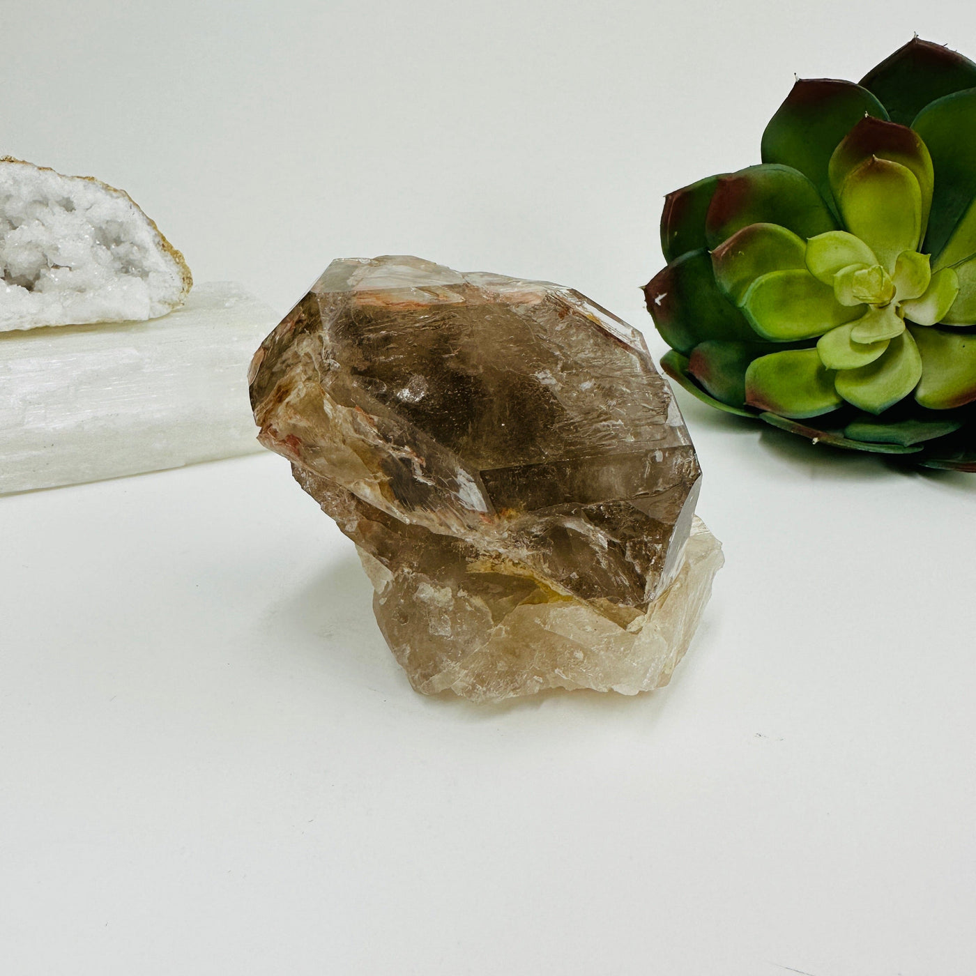 Smokey quartz cluster with decorations in the background