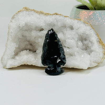 black obsidian arrowhead with decorations in the background