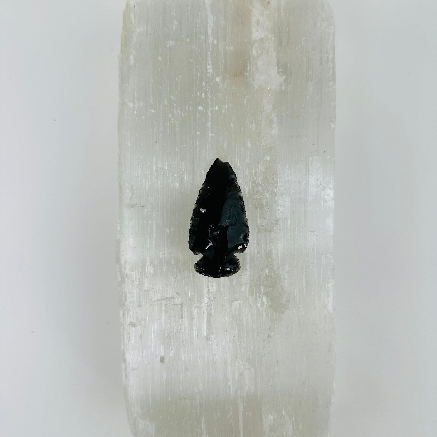 backside of obsidian arrowhead on selenite background