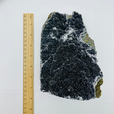 black druzy amethyst cut base next to a ruler for size reference