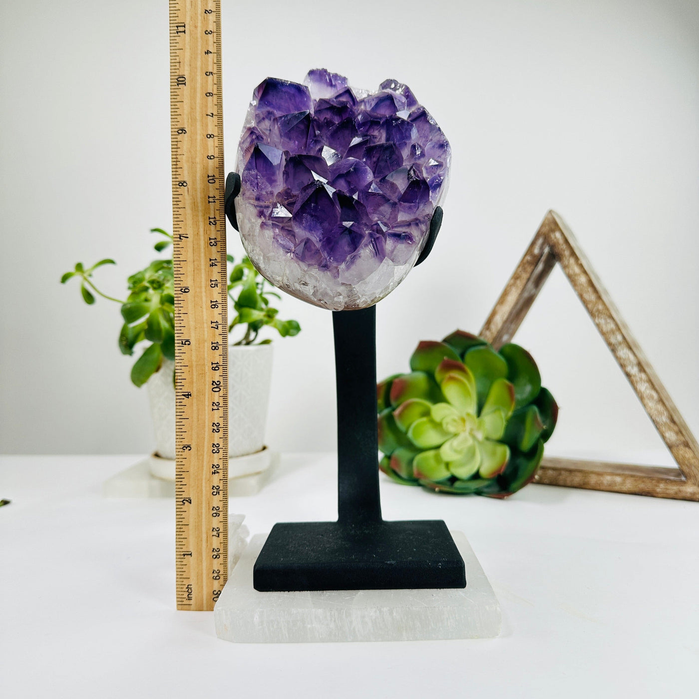 polished amethyst on stand next to a ruler for size reference