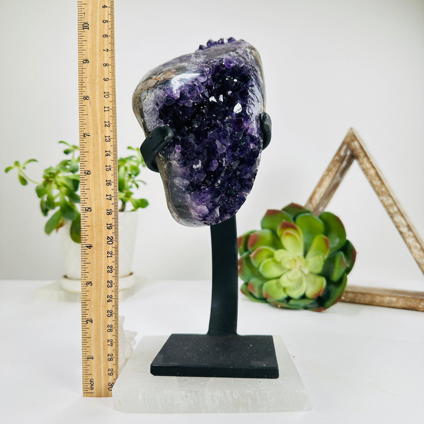 side view of semi polished geode on stand next to a ruler for size reference