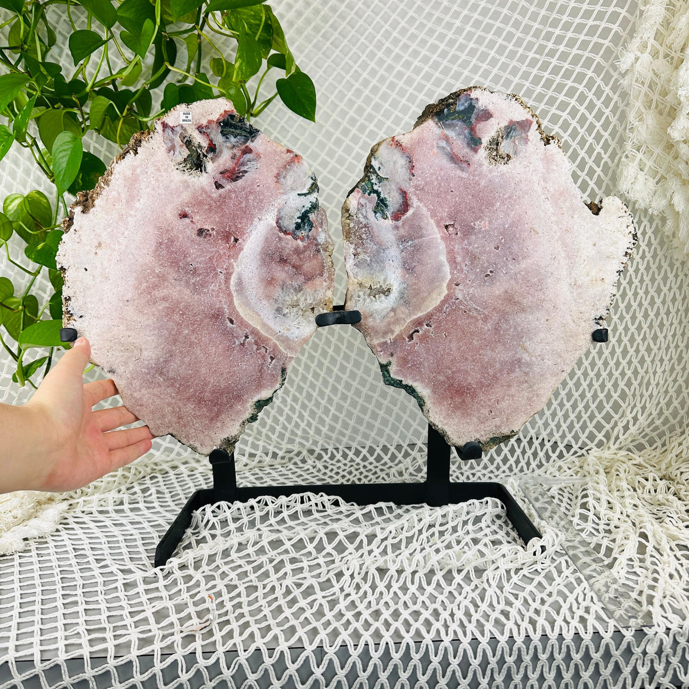 Hand next to Pink amethyst wings with decorations in the background