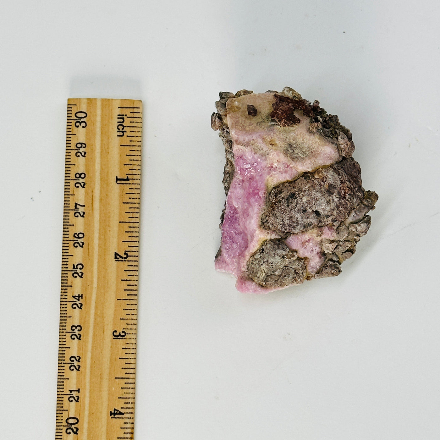 pink cobalto calcite cluster next to a ruler for size reference