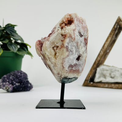 side view of Pink amethyst on metal stand with decorations in the background