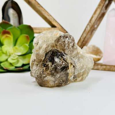 smokey quartz cluster with decorations in the background