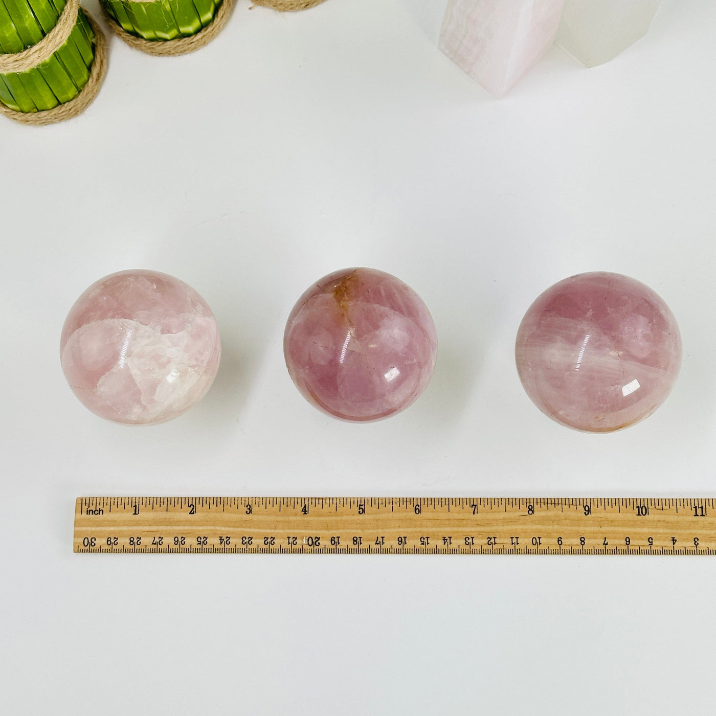 rose quartz spheres next to a ruler for size reference