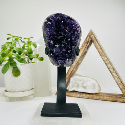 polished amethyst on stand with decorations in the background