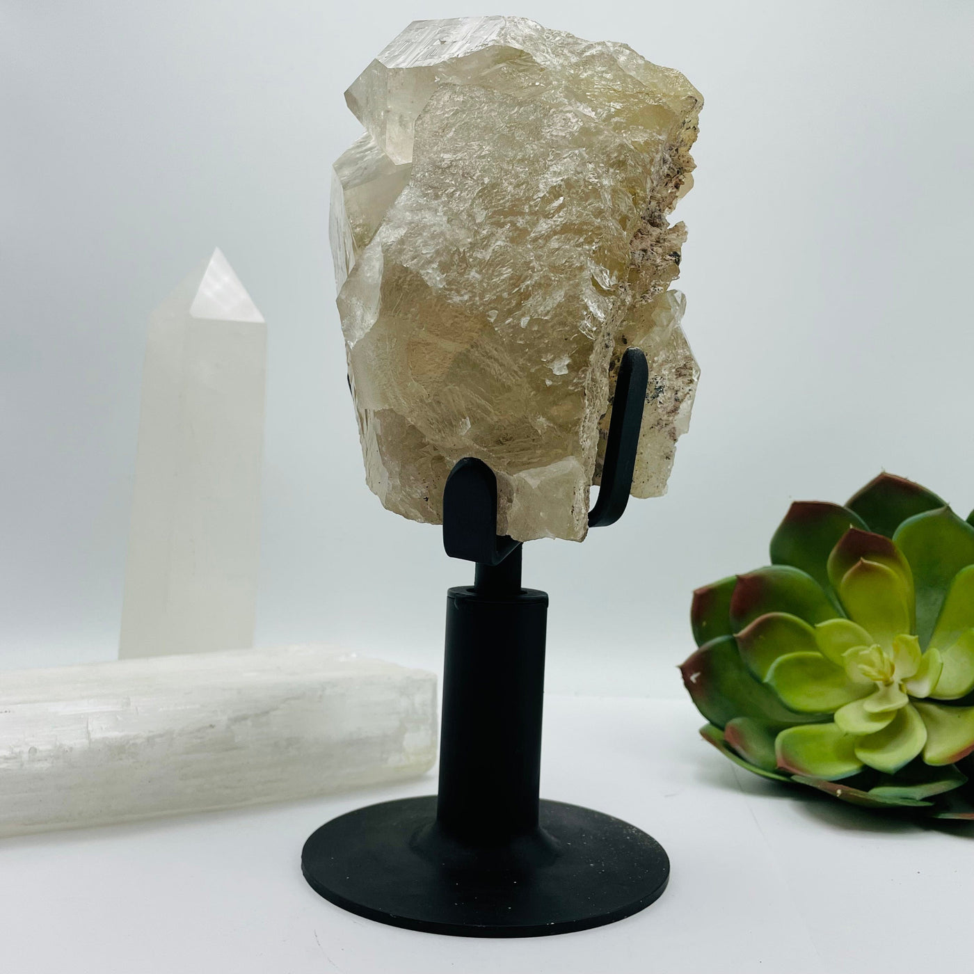 side view of Rutilated Crystal Quartz Cluster on Metal Stand with decorations in the background