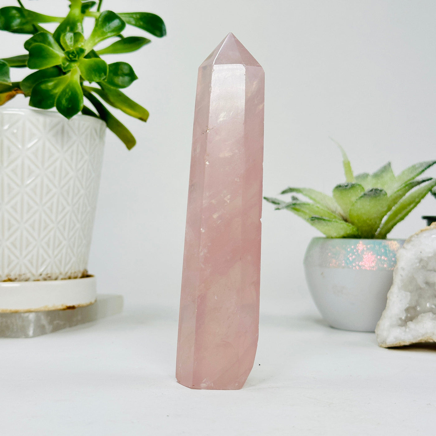rose quartz polished point with decorations in the background