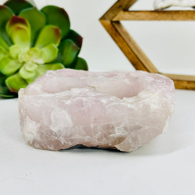 side view of rose quartz candle holder with decorations in the background