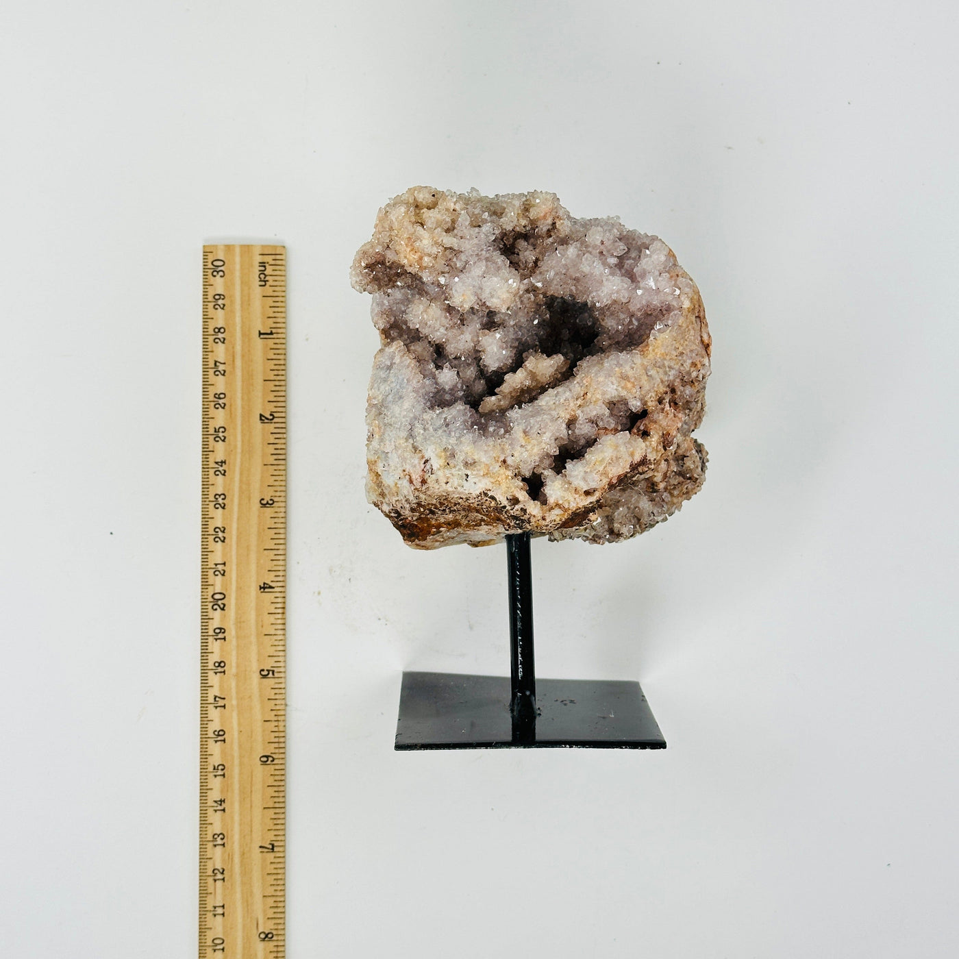 raw pink amethyst on metal stand next to a ruler for size reference