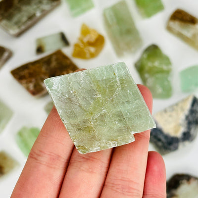hand holding up green calcite piece with others in the background