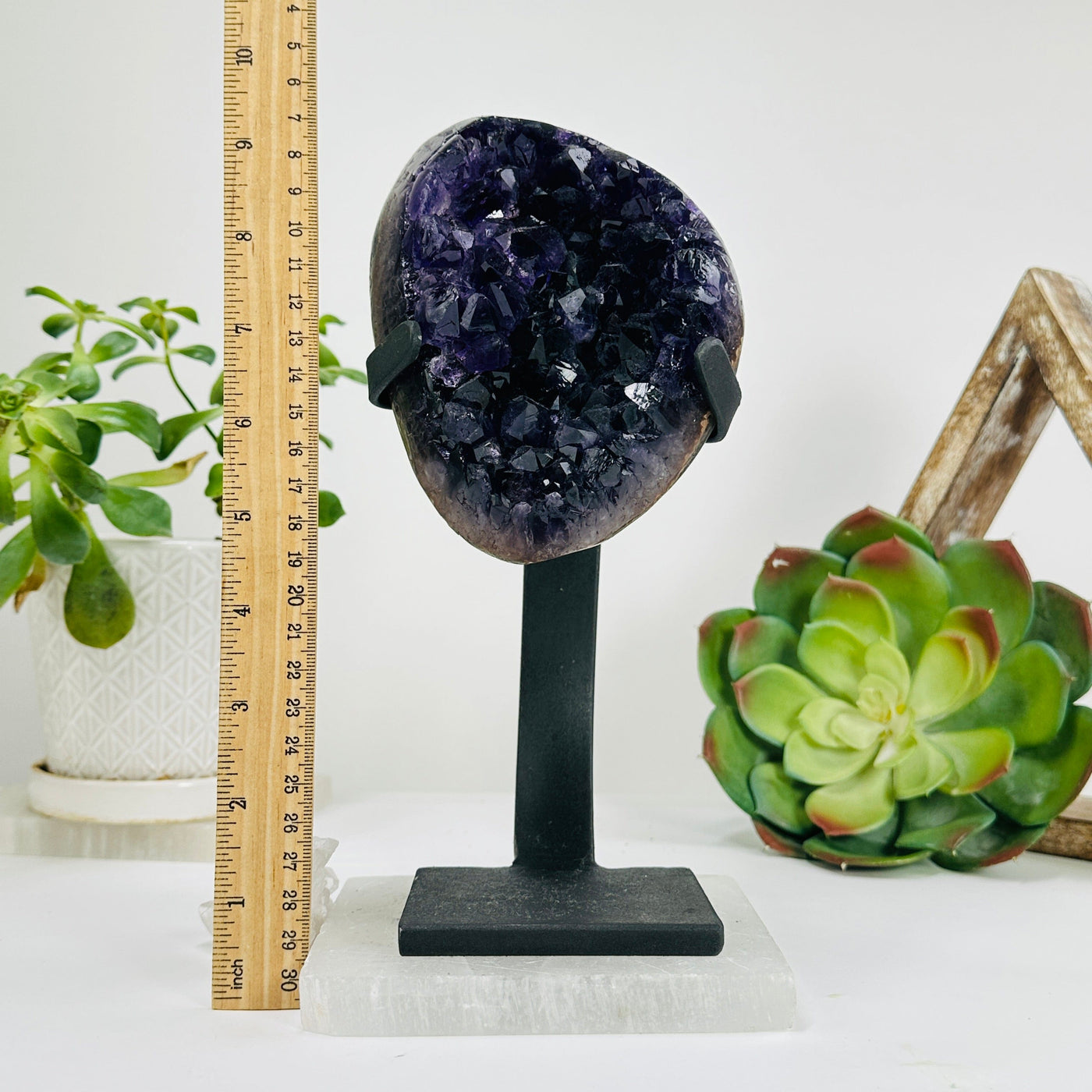 polished amethyst on stand next to a ruler for size reference