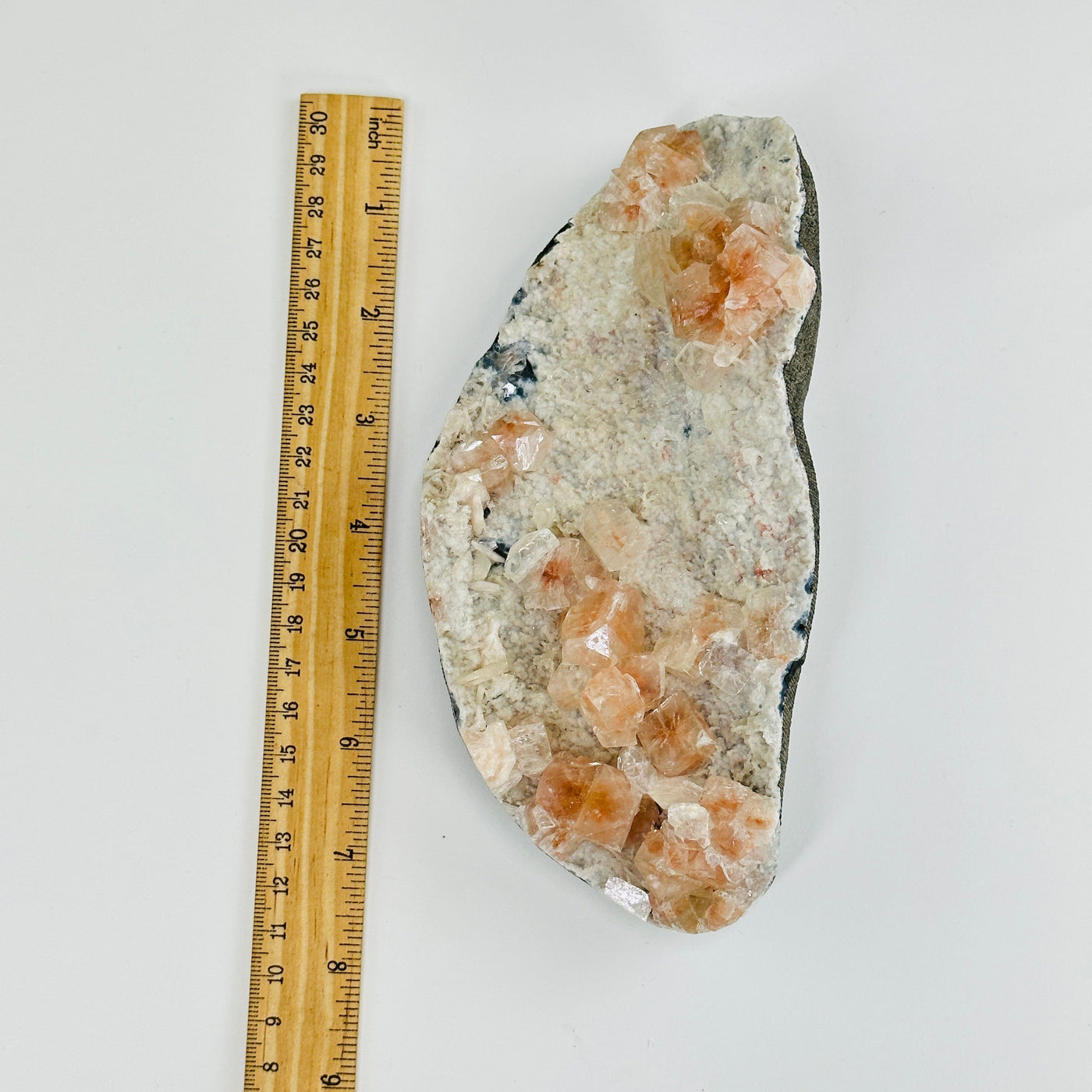 peach apophyllite on matrix next to a ruler for size reference