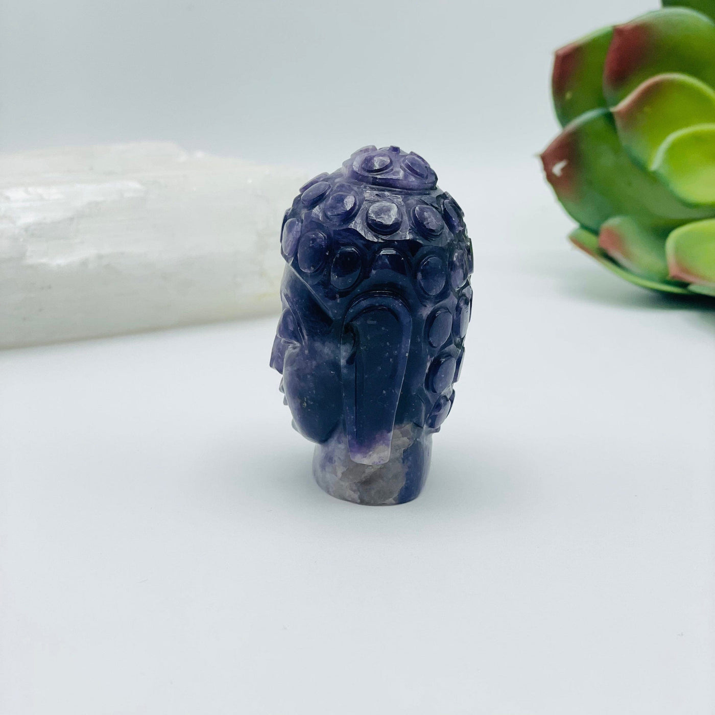 side view of Lepidoite Buddha head with decorations in the background