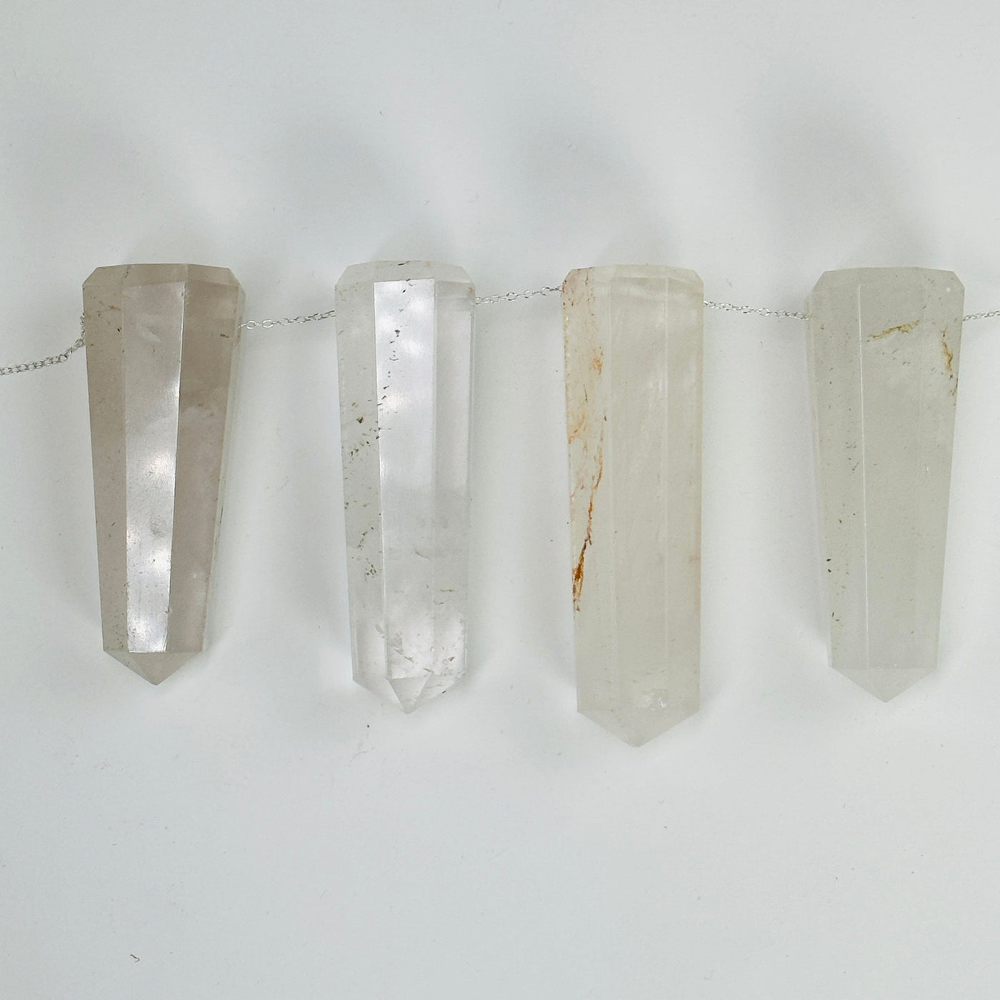 crystal quartz obelisk points with a chain through them on white background