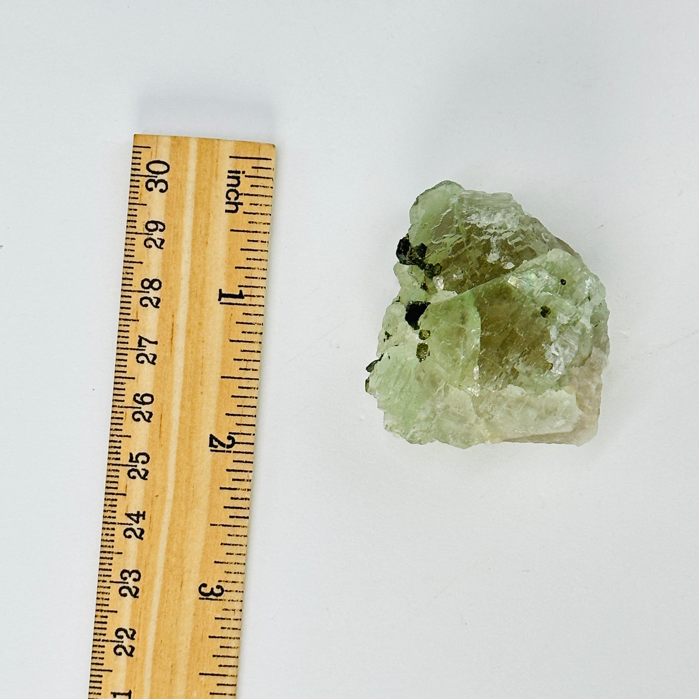 green fluorite with epidote growth next to a ruler for size reference