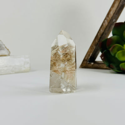 side view of Polished lodalite point with decorations in the background