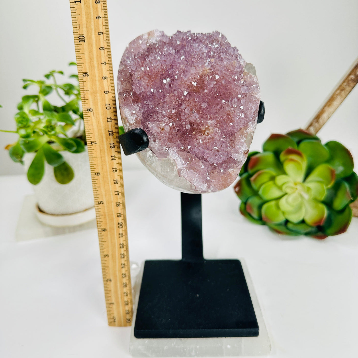 polished amethyst with stand next to a ruler for size reference