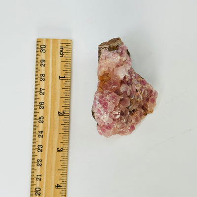 pink cobalto calcite formation next to a ruler for size reference
