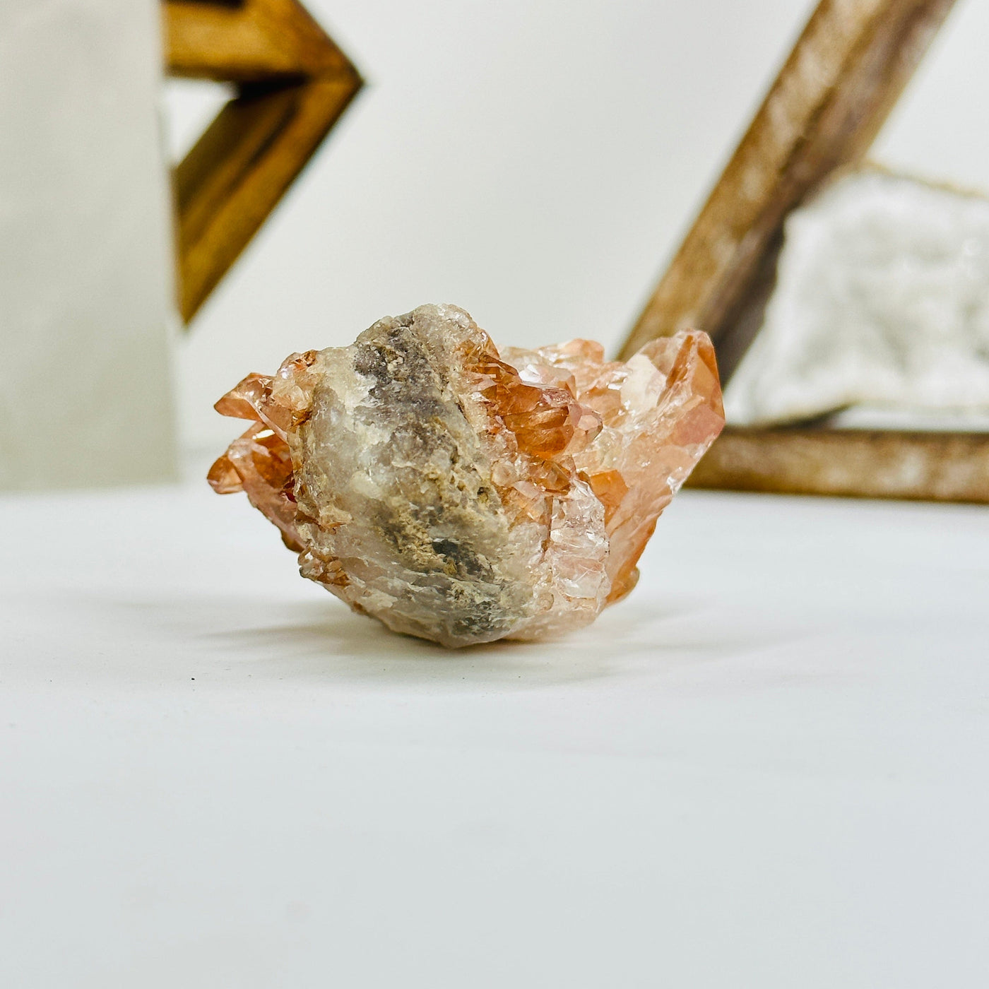 side view of tangerine quartz cluster with decorations in the background