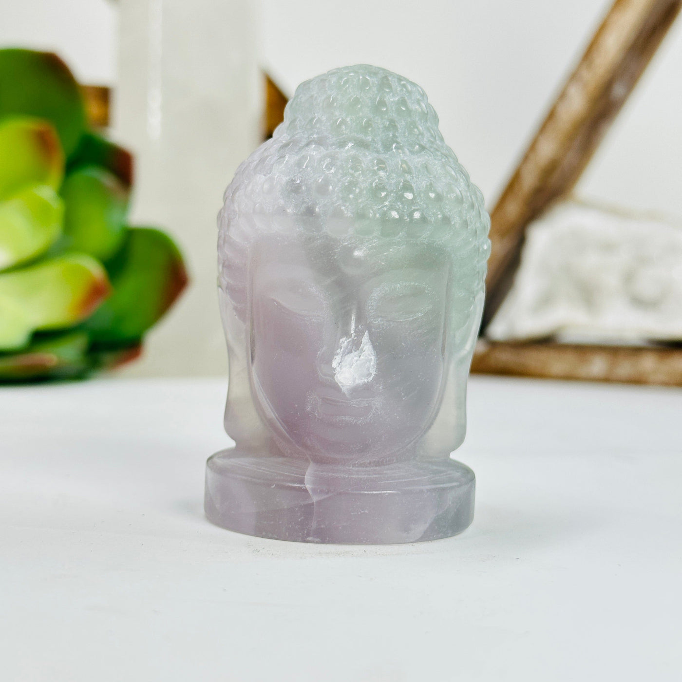 fluorite buddha head with decorations in the background