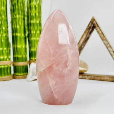 rose quartz polished cutbase with decorations in the background