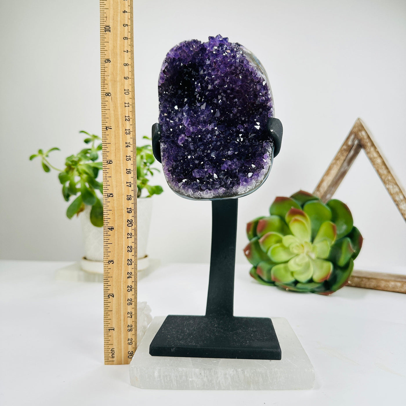 purple amethyst on metal stand next to a ruler for size reference