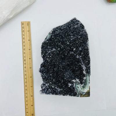 black druzy amethyst cut base next to a ruler for size reference