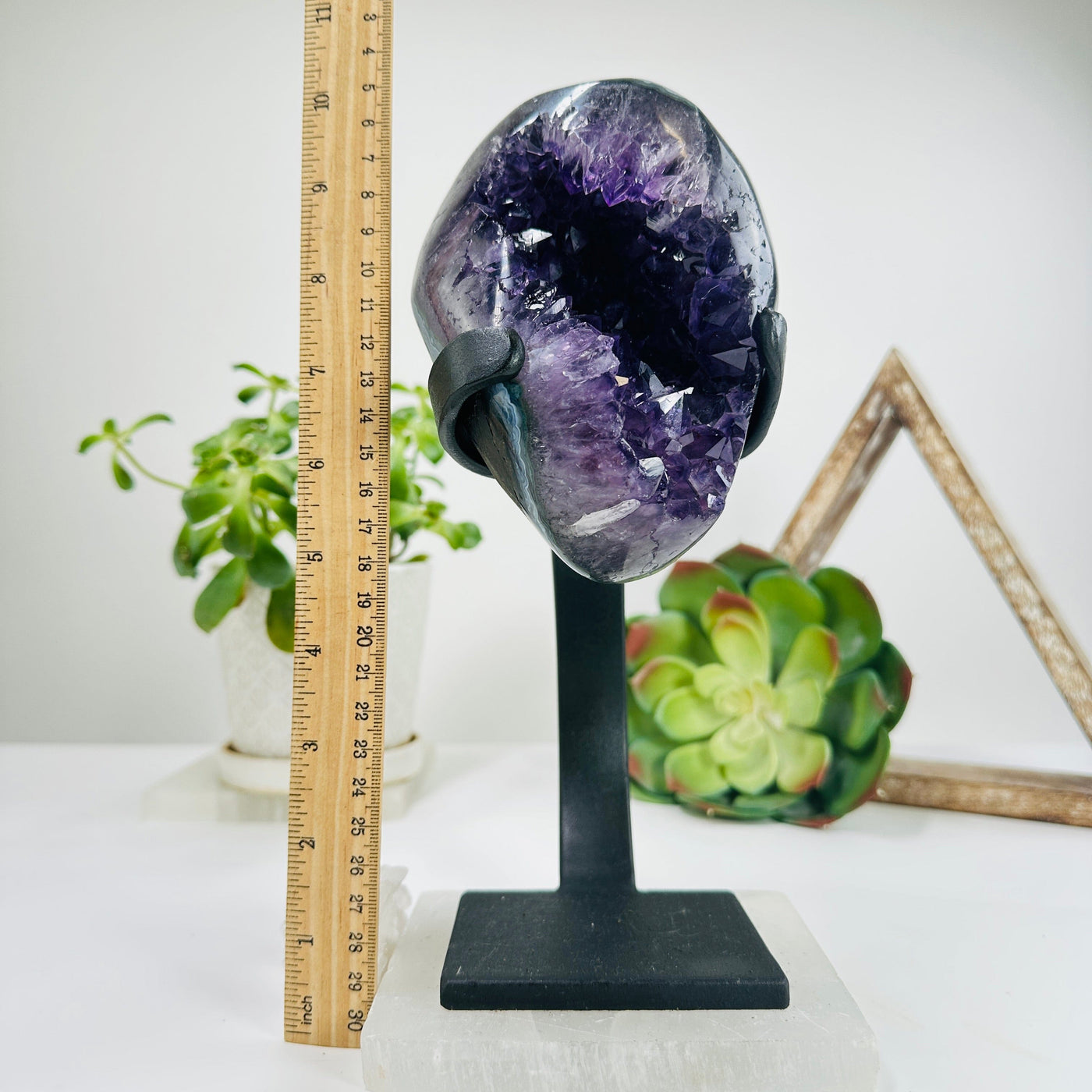 polished amethyst on stand next to a ruler for size reference