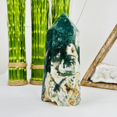 moss agate polished tower with decorations in the background