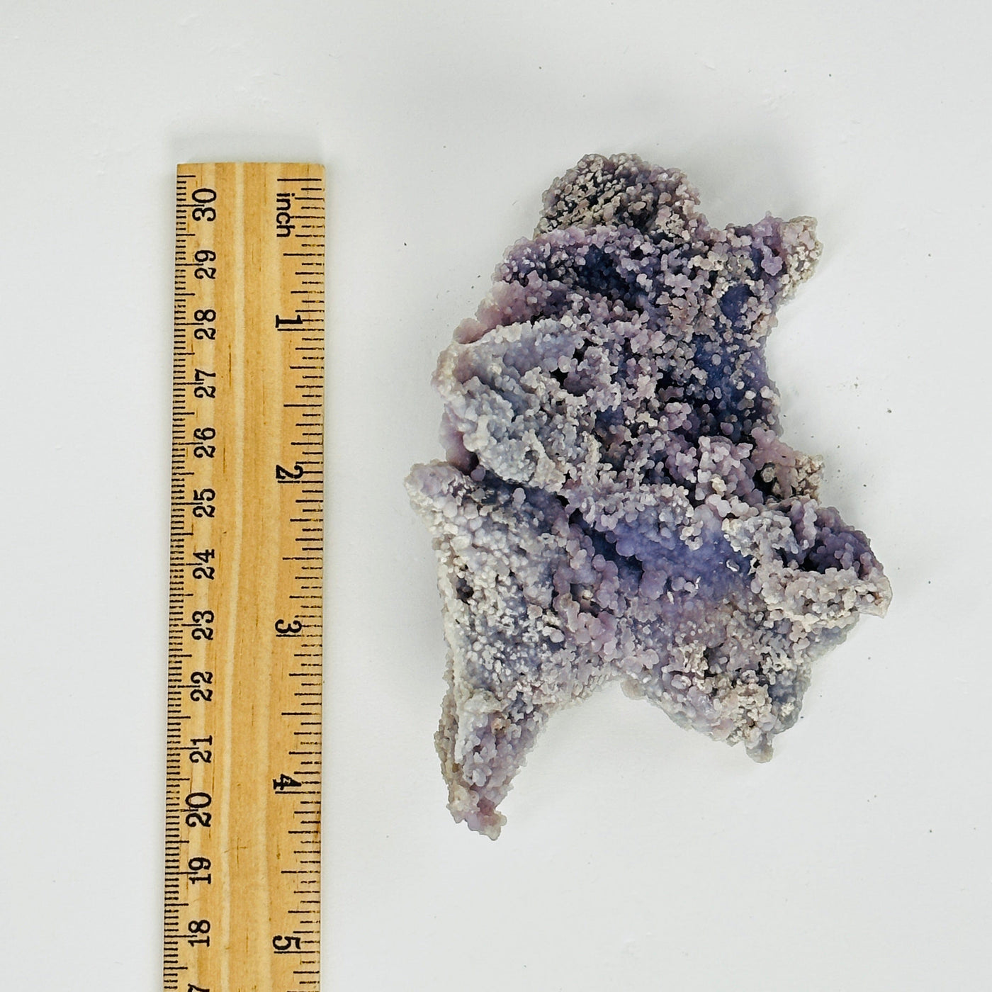 grape agate cluster next to a ruler for size reference