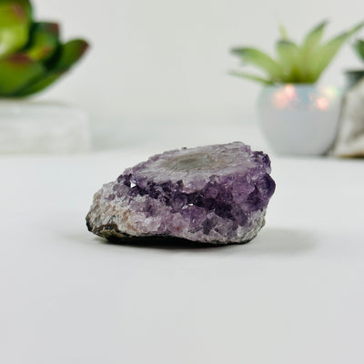 side view of amethyst stalactite cluster with decorations in the background