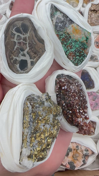 assorted minerals in a woman's hand and a box of assorted minerals.