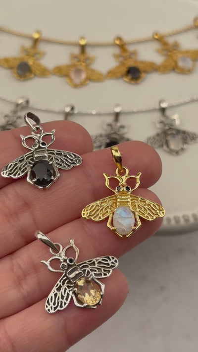 video of hand holding up crystal bee pendants with others in the background