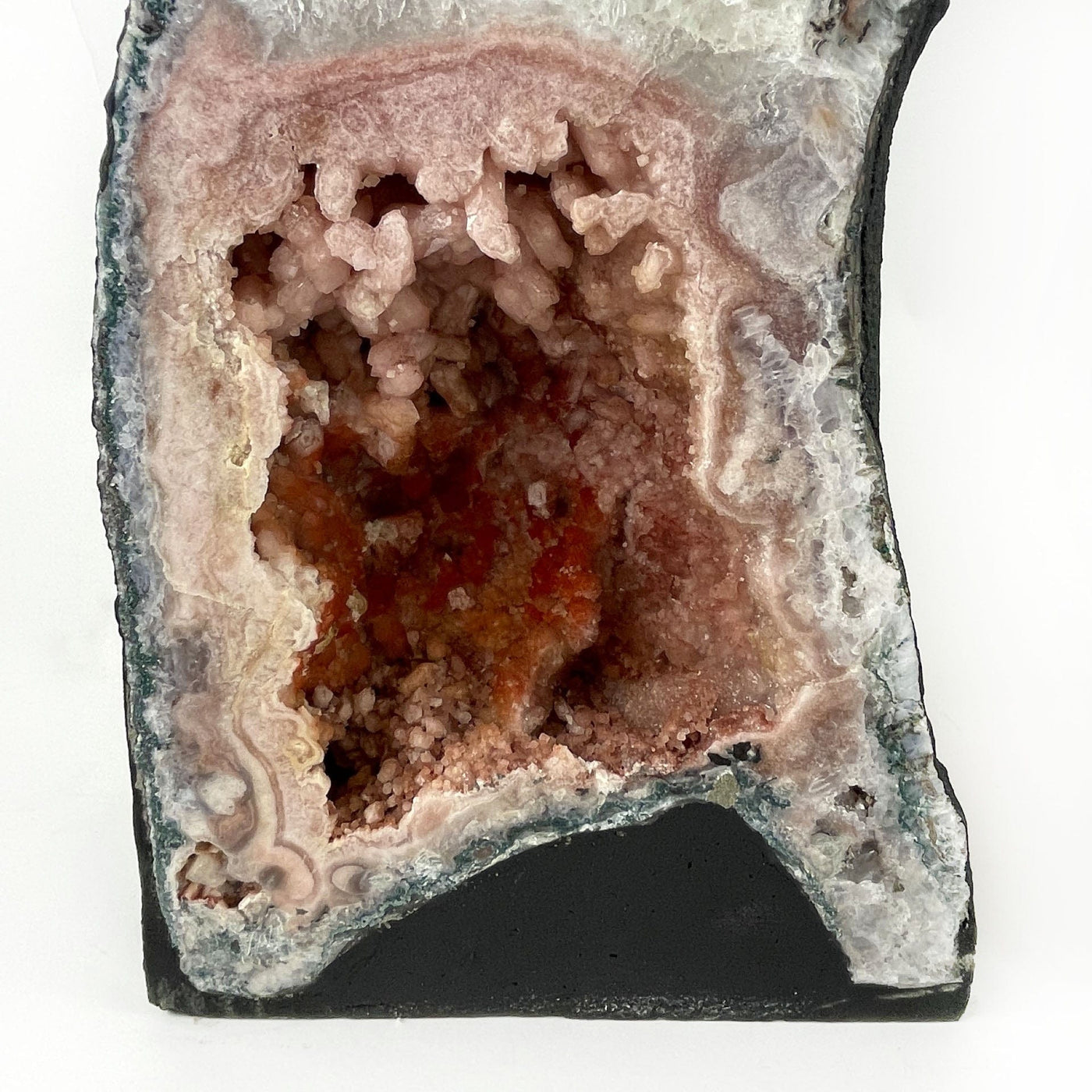 close up of one geode showing it has pink amethyst crystals and black base.
