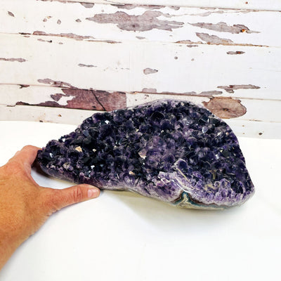 Amethyst Crystal Cluster side view with a hand for size reference