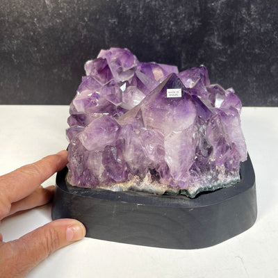 Amethyst Crystal Cluster on Wooden Base with a hand for size reference
