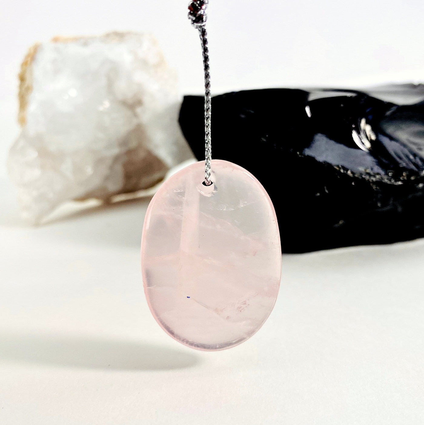 Rose Quartz Tumbled Pendant with other crystals blurred in the background