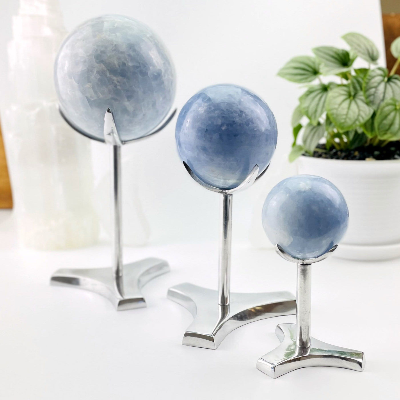 Small, medium, and large metal sphere holders with calcite spheres on them as an example of crystals they hold.