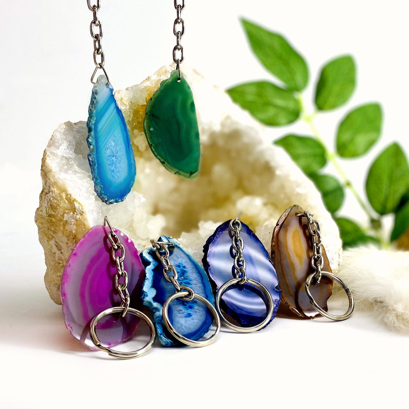 Close up of agate keychains next to a geode with plants in the background.