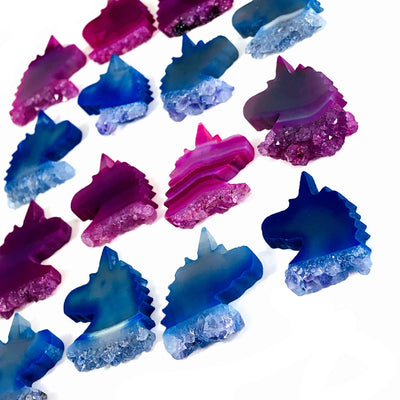 Pink and blue agate unicorn heads being displayed on a white background.