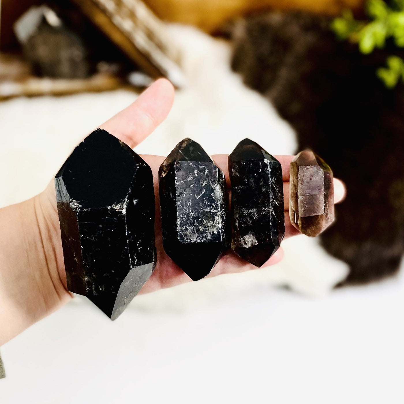 four different smokey quartz raw double point weights in hand for size reference and possible variations