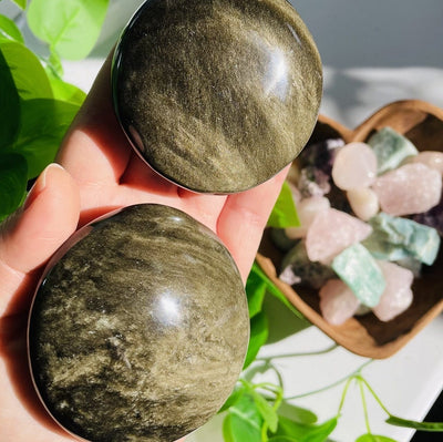 gold sheen obsidian round palm stones in hand for size reference 