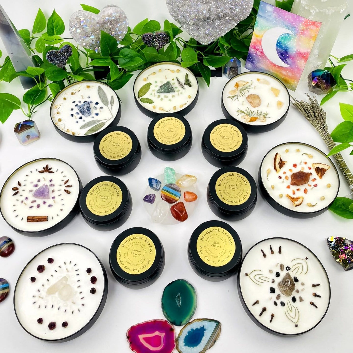 Diffrent types of Chakra Candle Tins arranged in a circle with crystals and plants
