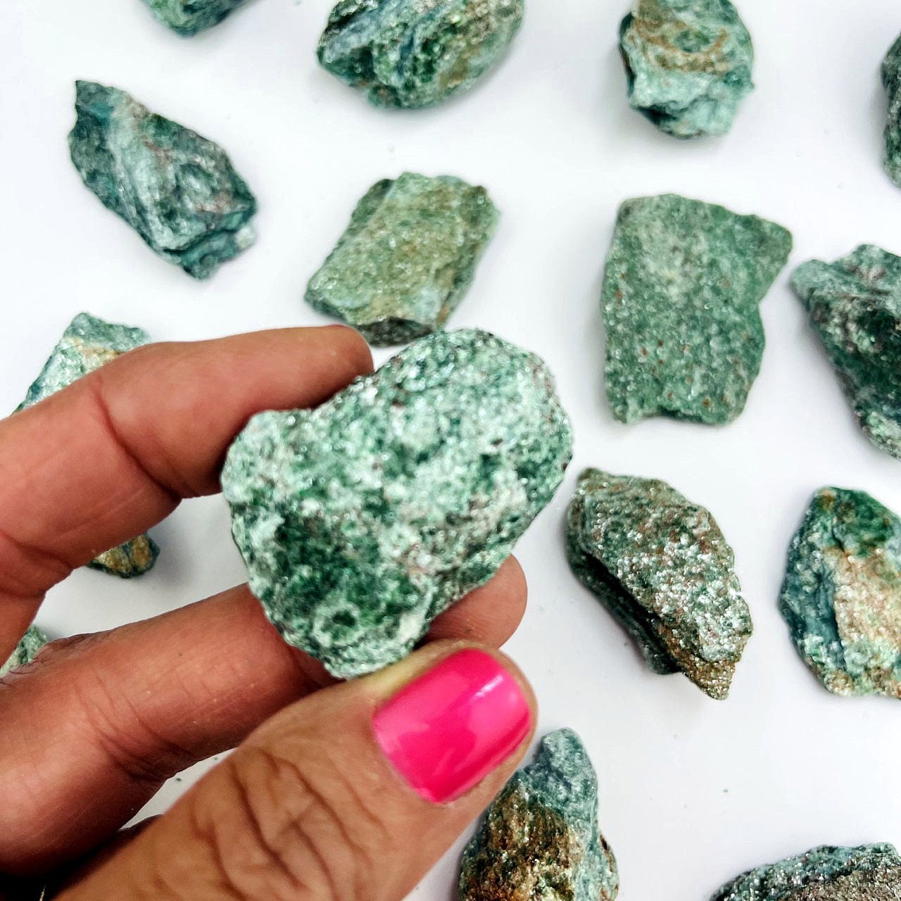 Fuchsite Natural Stone in a hand and other stones behind