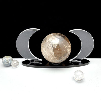 Acrylic Sphere Holder Crescent Moons holding a sphere with a couple crystals surrounding.
