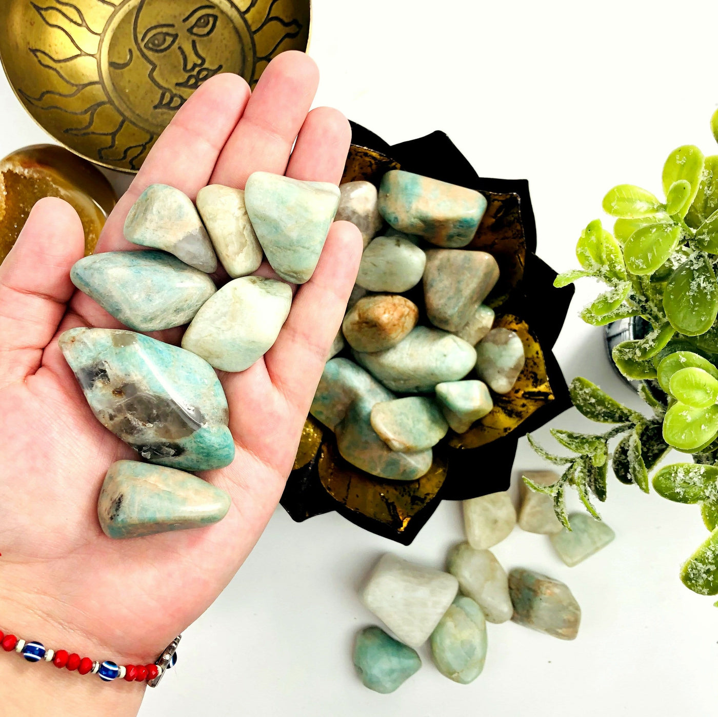 Tumbled stones are being held for size reference.