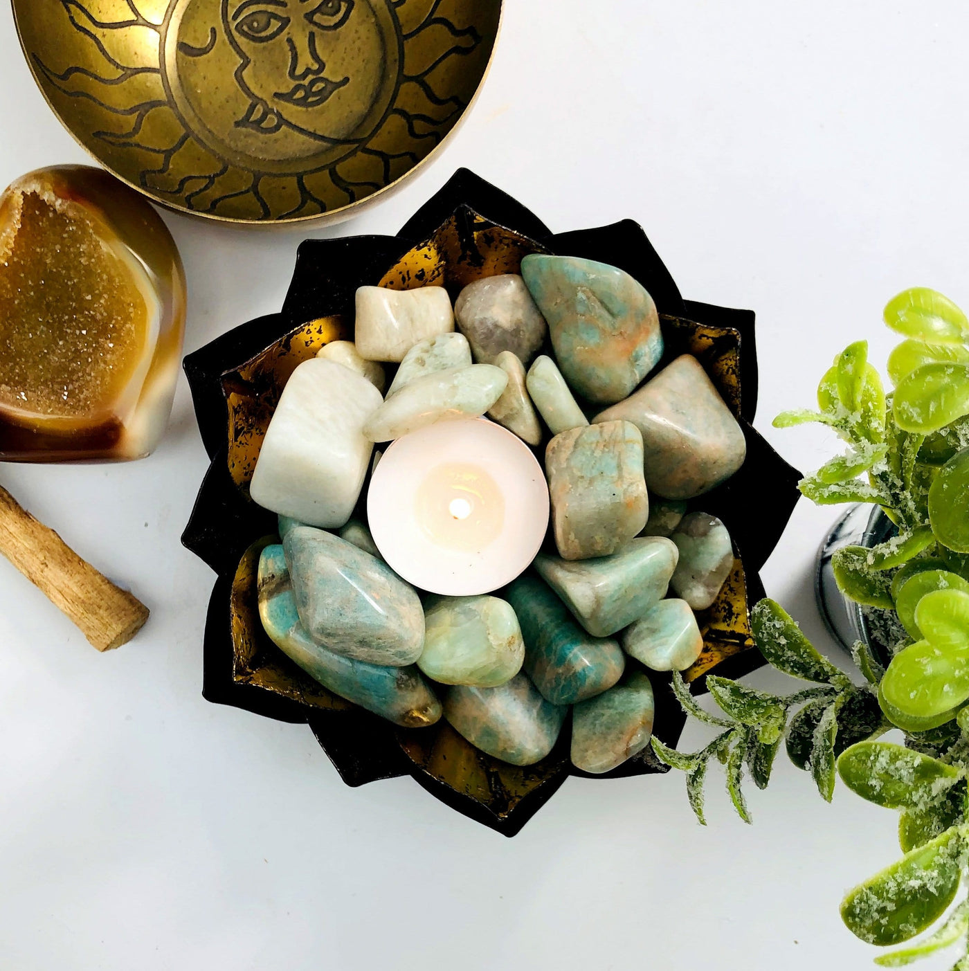 amazonite tumbled stones in a copper bowl with a candle in the middle.